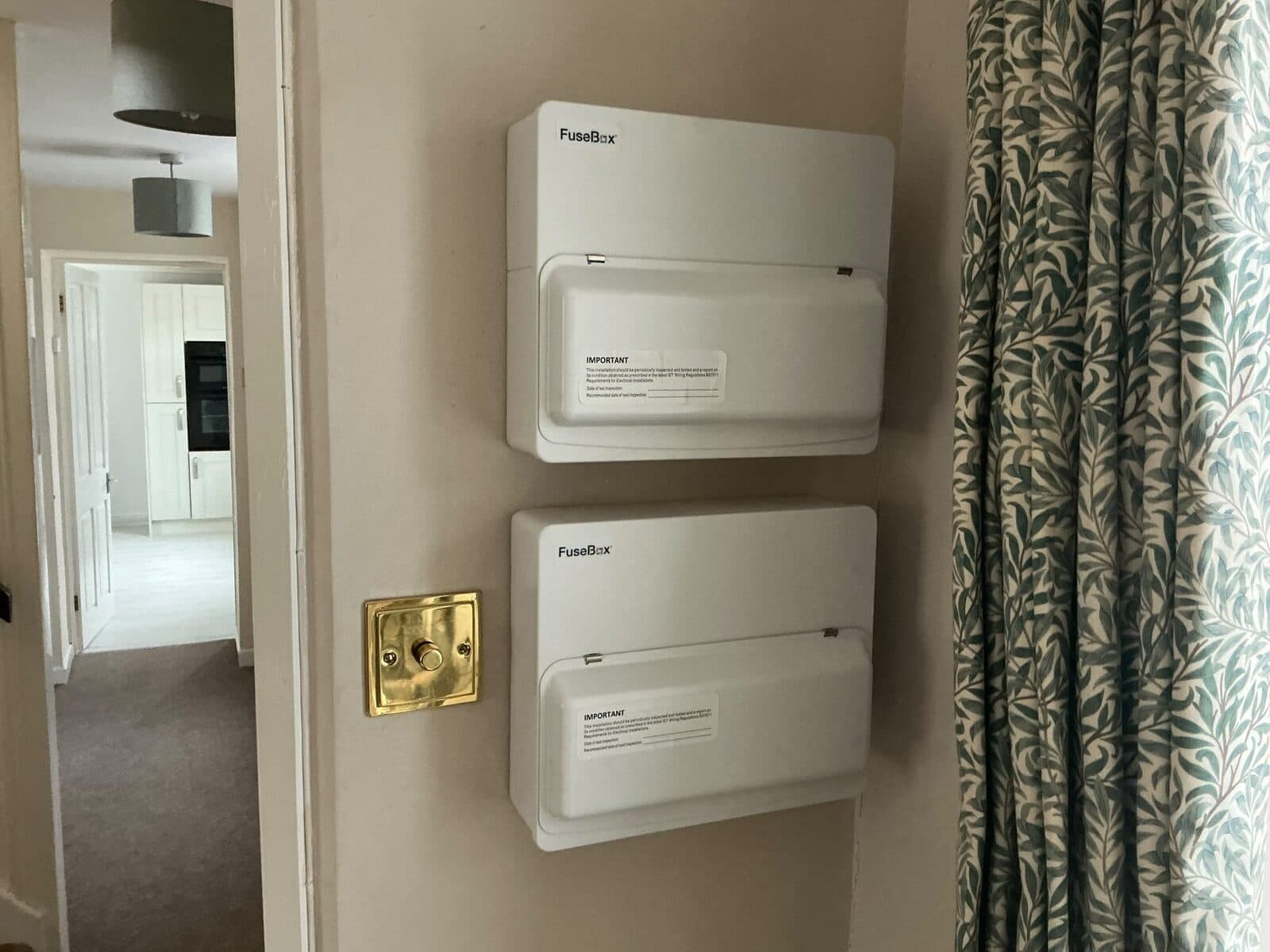 Two new consumer units fitted one above the other on a hallway wall